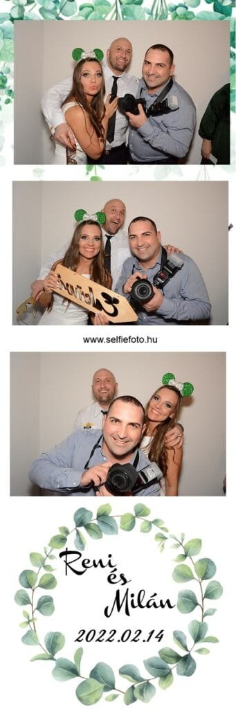 Selfiebox esküvőre – különleges pillanatok kreatív fotóautomatával. Esküvői pár és fotós vidám pillanata selfiebox előtt. A menyasszony zöld-fehér füles hajpántot visel, akár egy "Esküvő" táblát tart. A vőlegény és a fotós mosolyognak, akkor a kamera felé néznek.