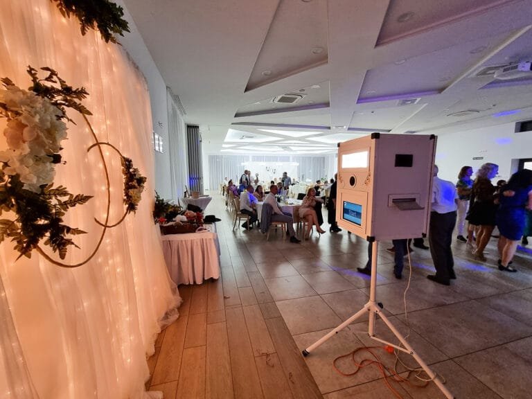 Elegáns esküvői helyszín, ahol egy fotóautomata várja a háttérben zajló vacsora és tánc közben. A dekoráció romantikus fényfüzérekkel és virágdíszekkel egészíti ki a hangulatot. Tökéletes választás esküvőkre, évfordulókra, vállalati rendezvényekre vagy születésnapokra, hogy felejthetetlen pillanatokat rögzítsen! Fotóautomata bérlés.
